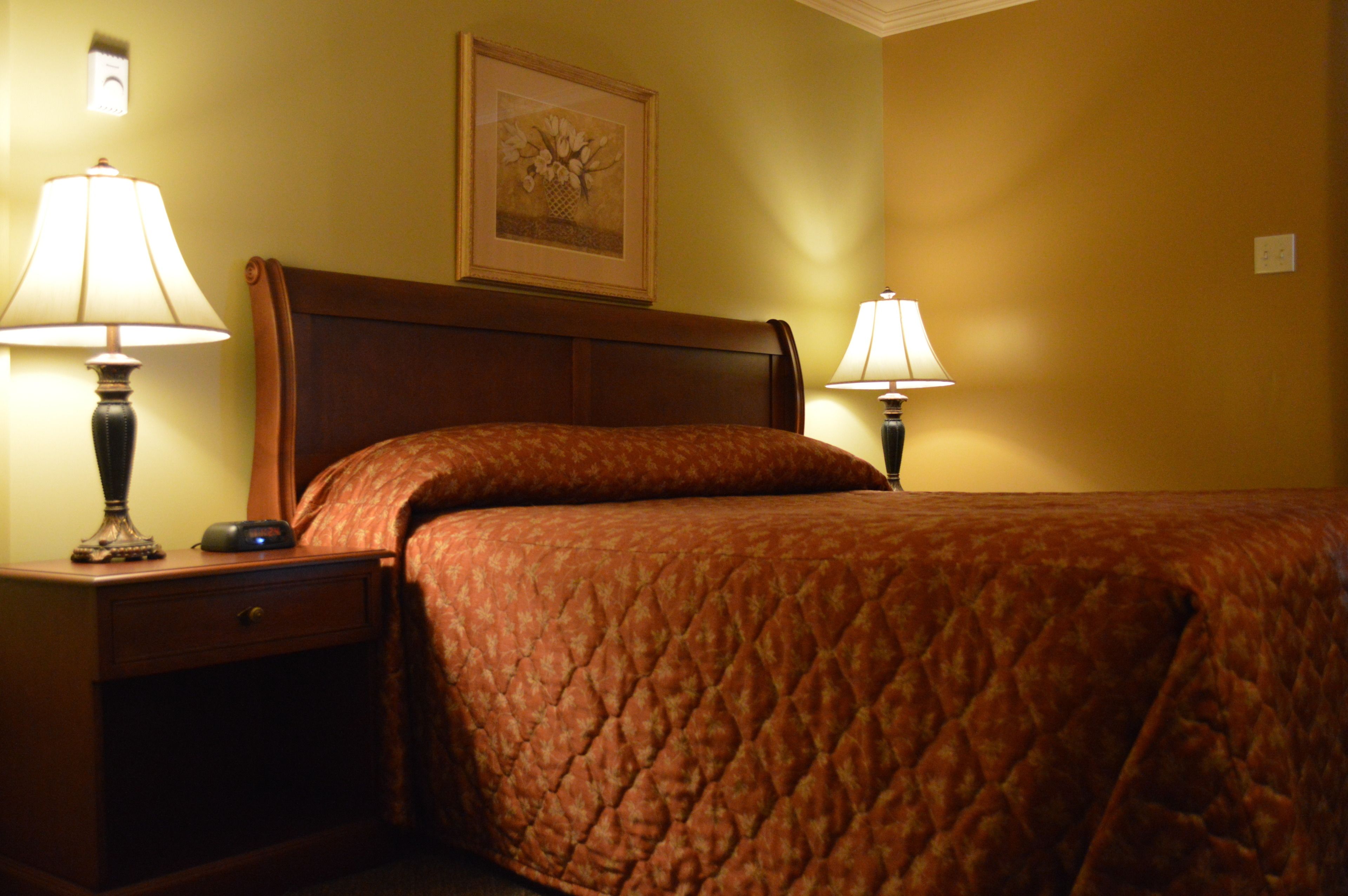 A hotel room with a bed, two bedside tables, and two lamps.