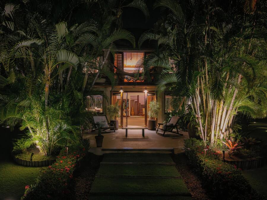 A tropical resort with a central building, surrounded by lush greenery and palm trees.