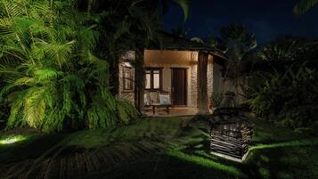 A house with a thatched roof, surrounded by dense tropical foliage.