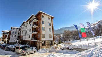 A multi-story hotel with balconies, a parking area, and flags.