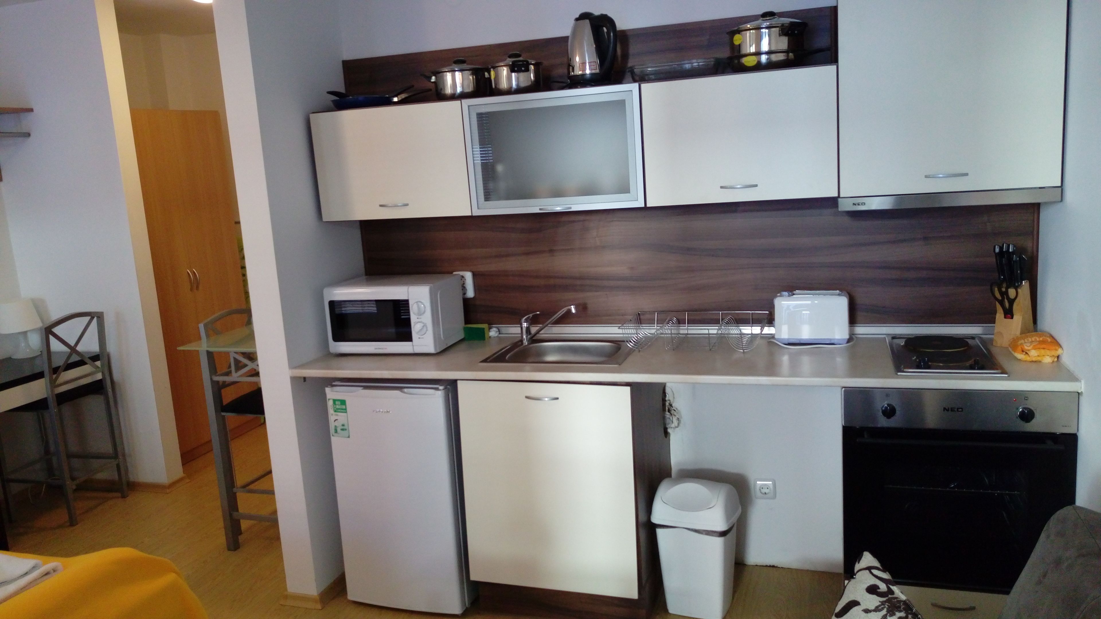 A compact kitchenette with a microwave, toaster, sink, and small refrigerator.
