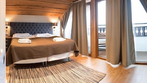 Une chambre avec un grand lit, un plafond en bois et un balcon agrémenté de rideaux.