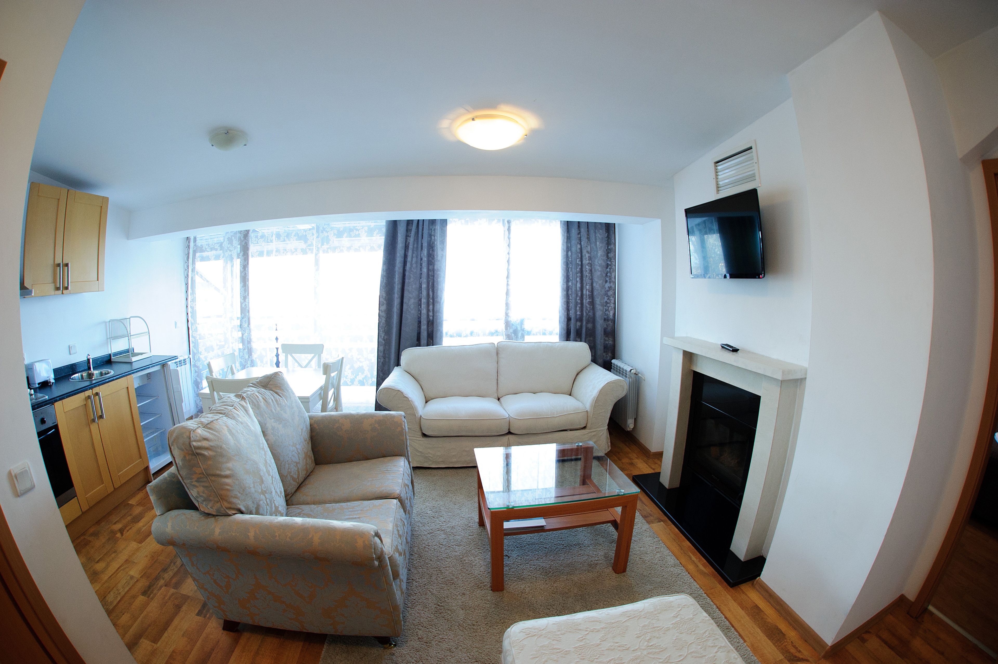 A living room with a sofa, a coffee table, a fireplace, and a TV mounted on the wall.