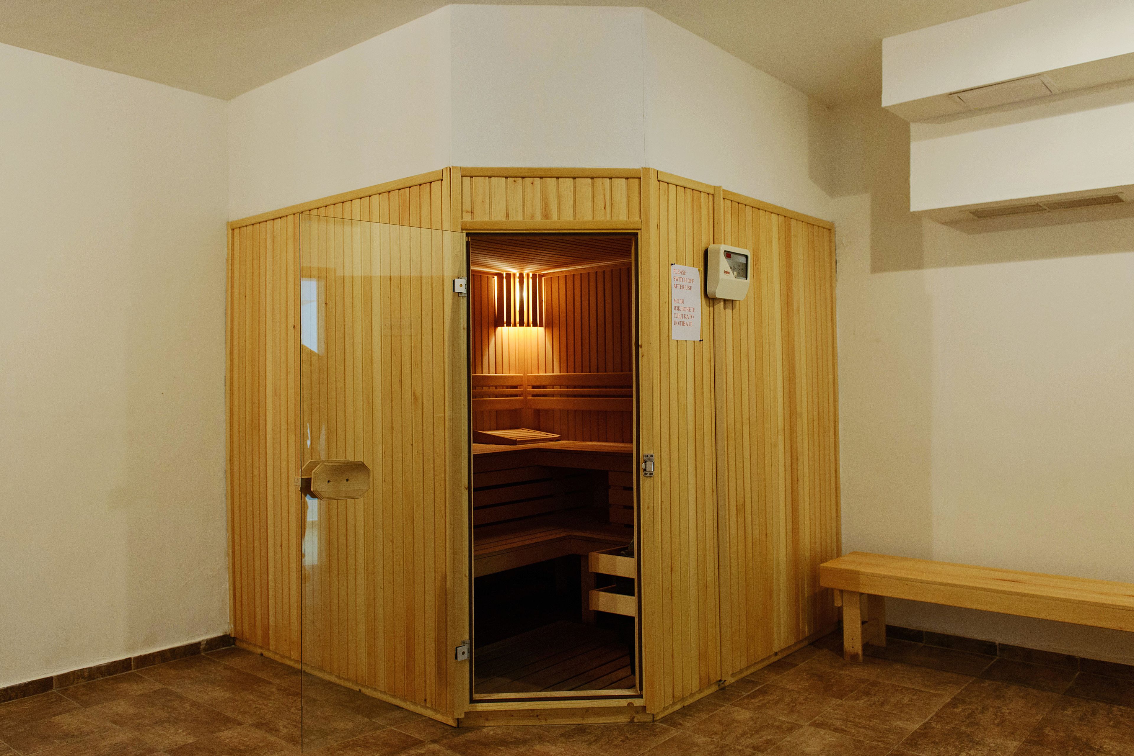 Una sauna de madera con un banco, una puerta y un panel de control.