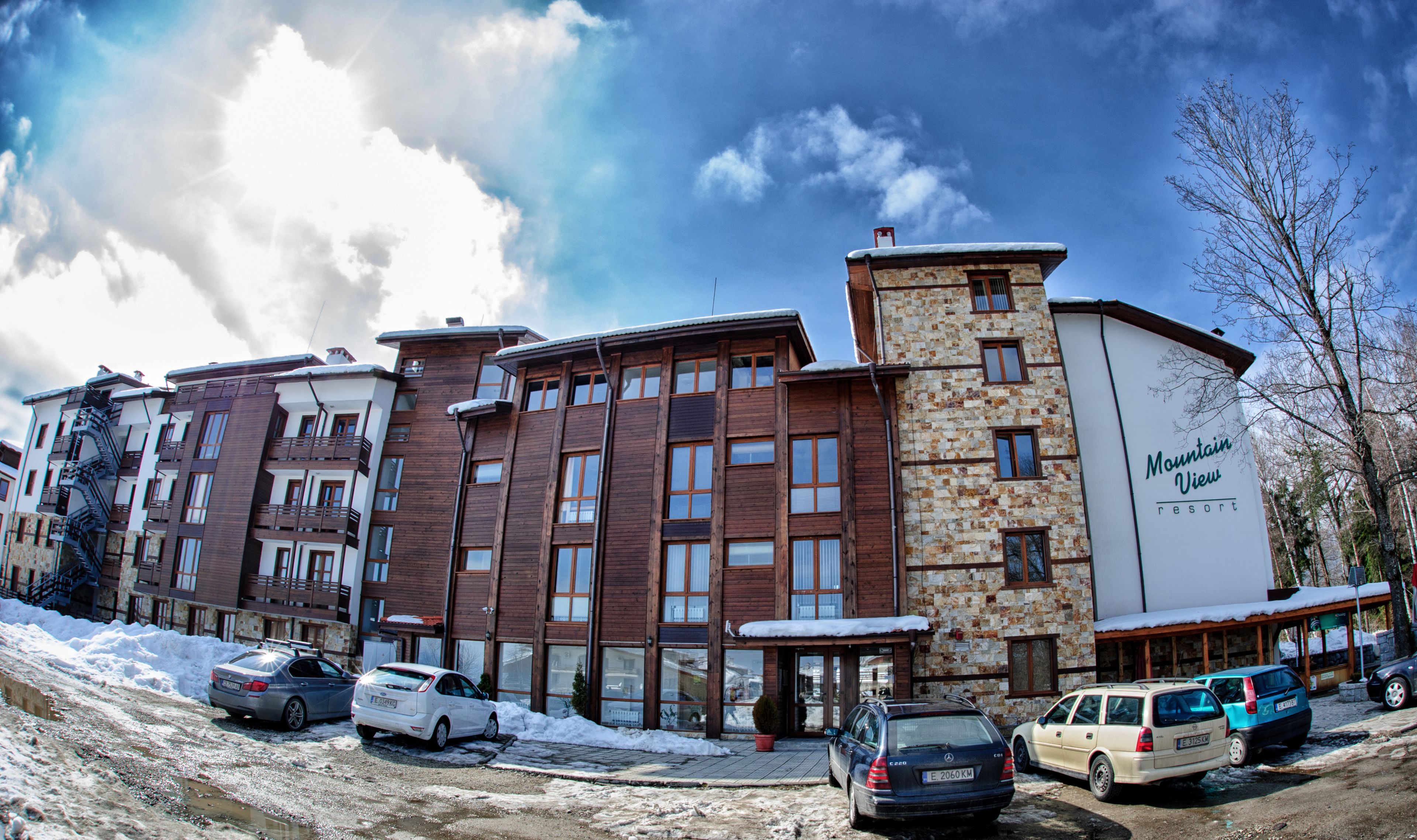 Un immeuble à plusieurs étages, doté d’une façade en pierre et de détails en bois, portant l’inscription « Mountain View Resort ».