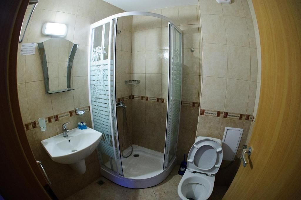 A bathroom with a shower enclosure, a sink, and a toilet.