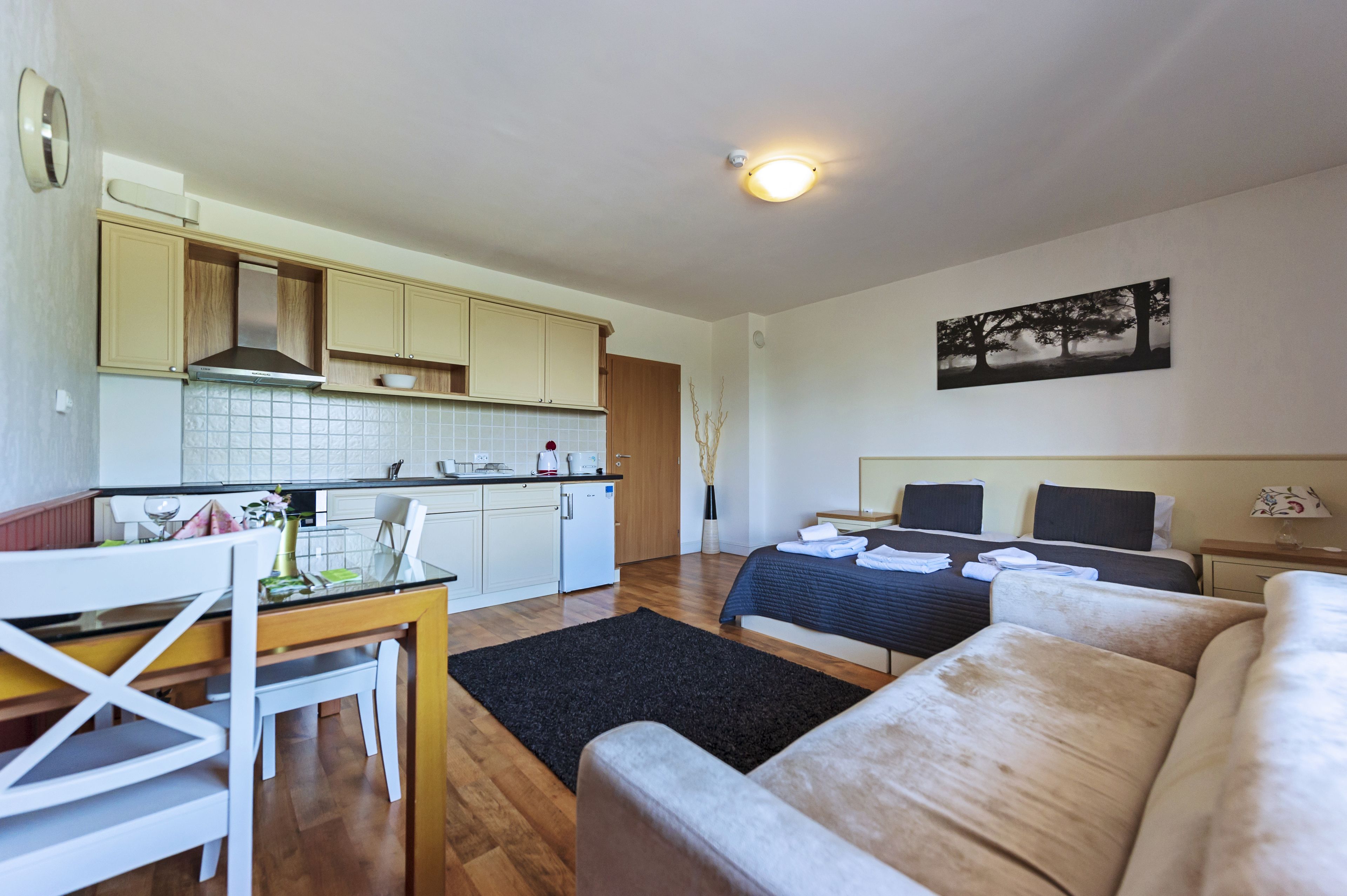 Un espacio habitable compacto con kitchenette, comedor y cama con cabecera.