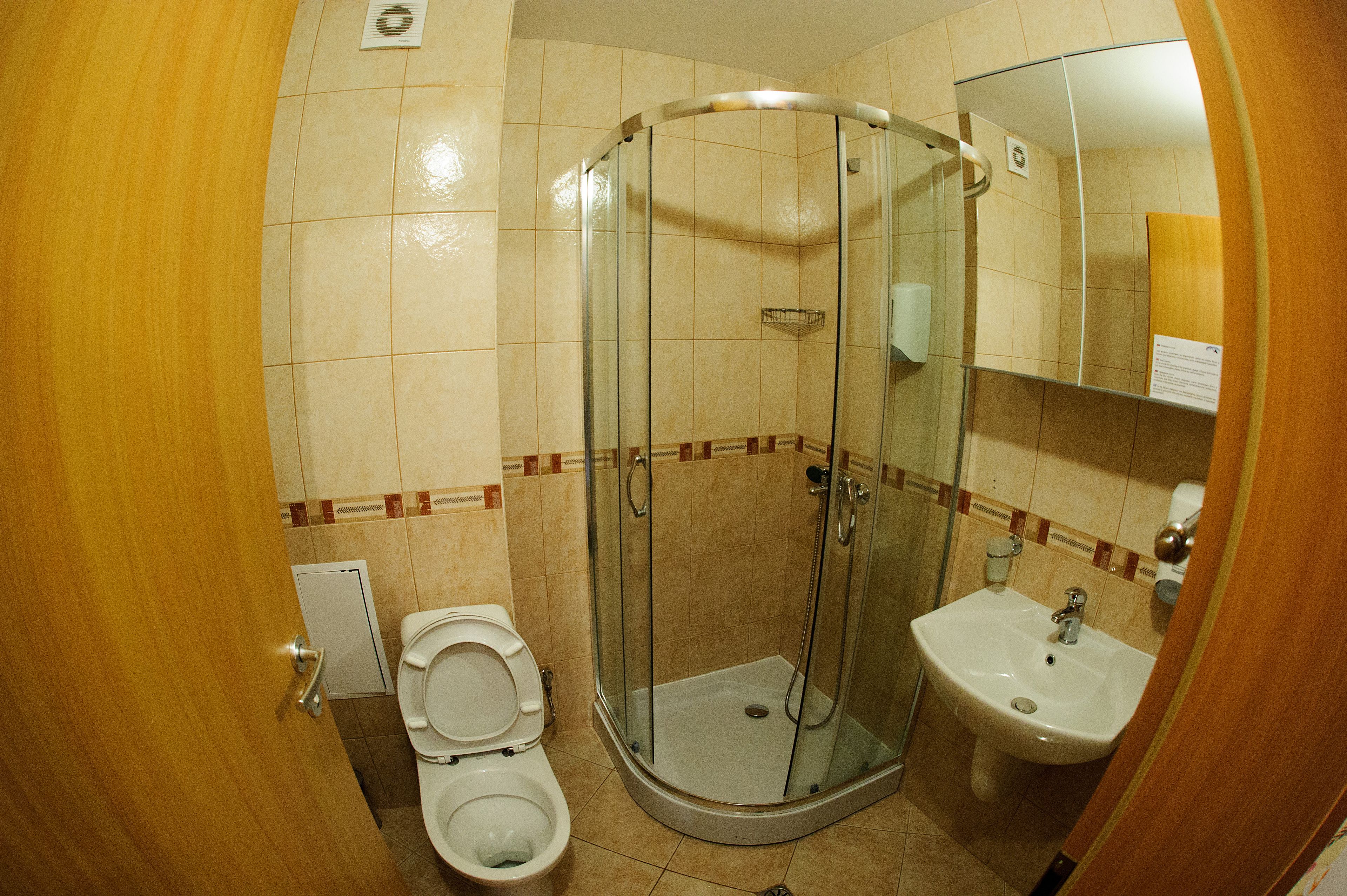 A compact bathroom with a glass-enclosed shower, a toilet, and a sink.