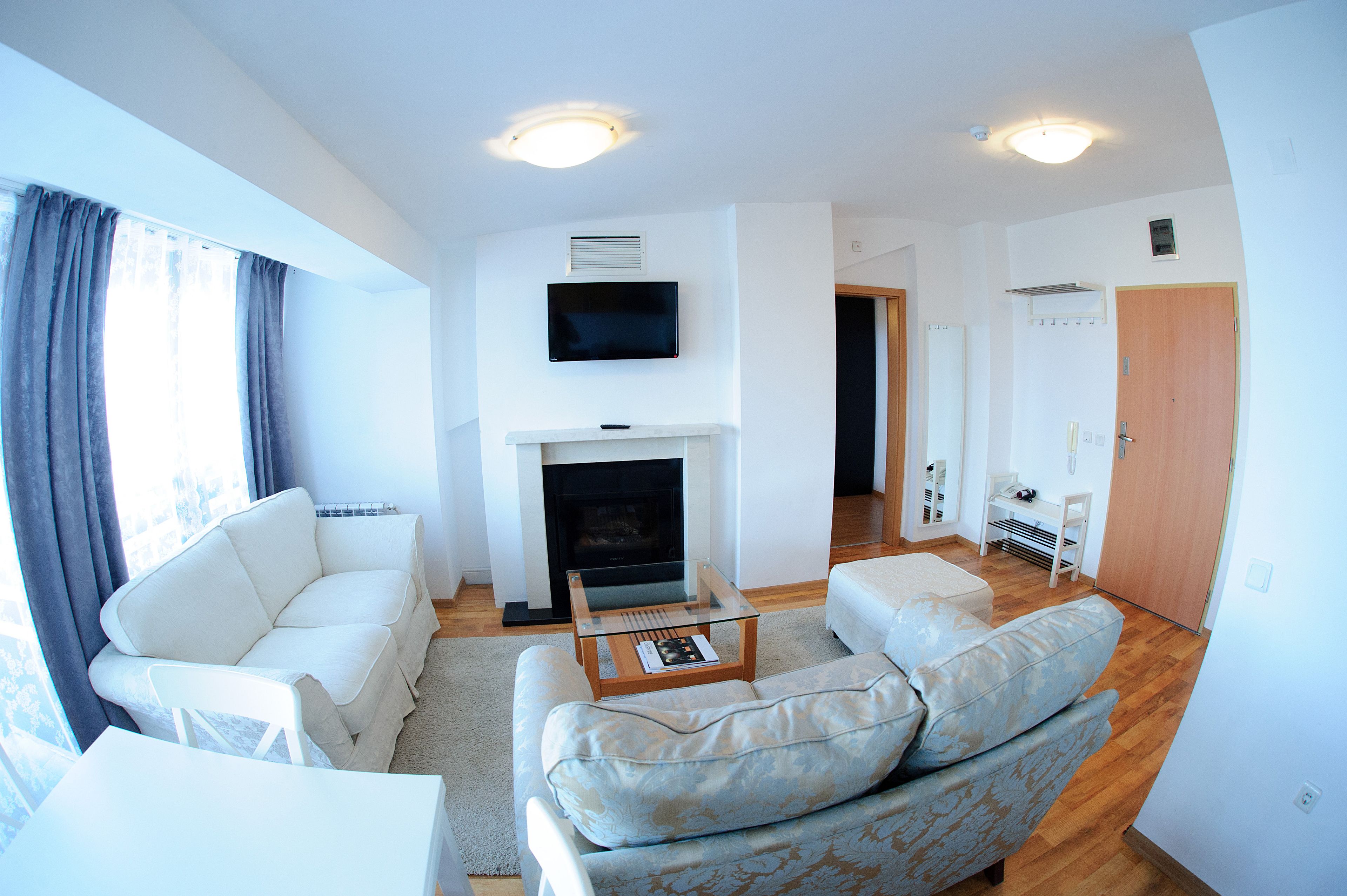 Una sala de estar moderna con chimenea, sofás blancos y un televisor de pantalla plana.