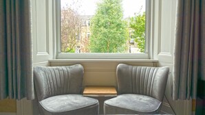 Ein Zimmer mit Fensterbank, ausgestattet mit zwei Sesseln und einem kleinen Tisch.
