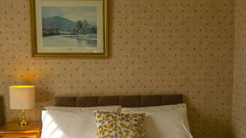 A neatly made bed with white linens and two towels folded at the foot.