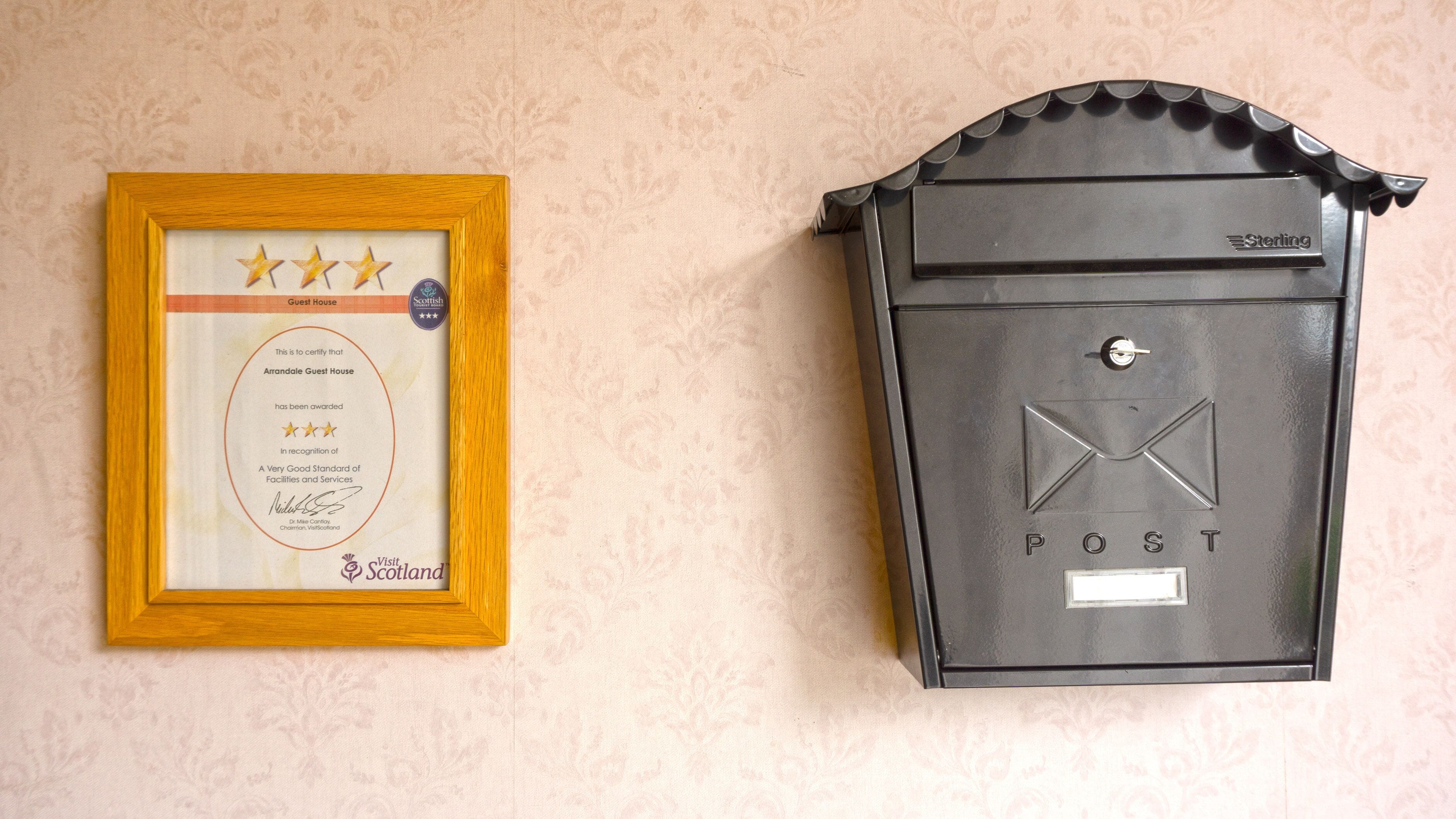 A framed certificate with a five-star rating and a black mailbox with 'P O S T' on it.