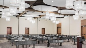 A conference room with multiple tables, chairs, and a podium. - The Hotel At Oberlin (Oberlin)