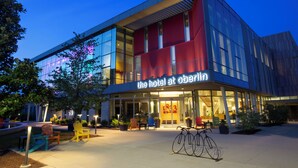 A modern hotel with a glass facade, outdoor seating, and a bicycle parked in front. - The Hotel At Oberlin (Oberlin)