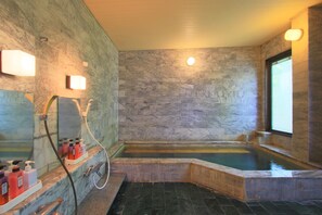 A bathroom with a marble wall, a bathtub, and a shower area. - Kounso (Yamanakako)