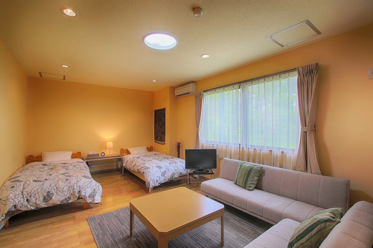 A room with two beds, a sofa, a TV, and a table.