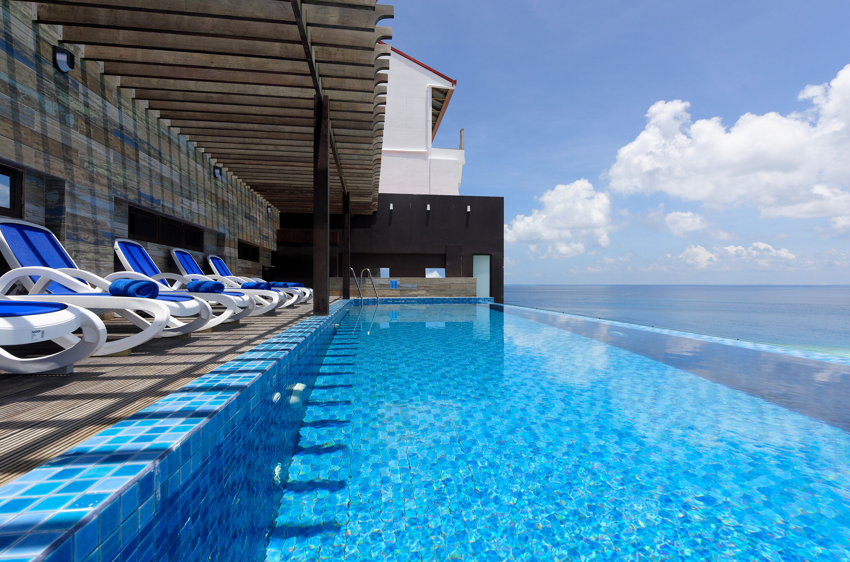 A poolside area with lounge chairs and a view of the ocean.