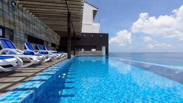 A poolside area with lounge chairs and a view of the ocean.