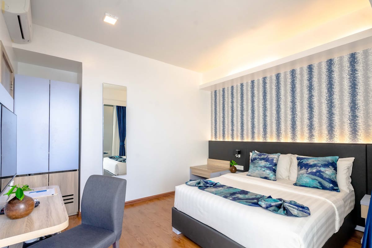 A modern hotel room with a bed, a desk, and a chair.