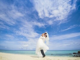 Una pareja abrazándose en una playa con cielos despejados y agua turquesa.