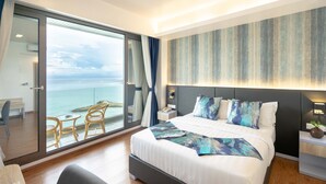 A modern hotel room with a large bed, a view of the sea, a balcony with chairs, and a nightstand with a lamp. - Arena Beach Hotel (Maafushi)