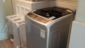 A front-loading washing machine with a control panel and a sticker on the door. - Spacious Apartment in Central Seoul (Seoul)