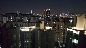 A nighttime view of a cityscape with illuminated buildings and a prominent skyscraper in the distance. - Spacious Apartment in Central Seoul (Seoul)