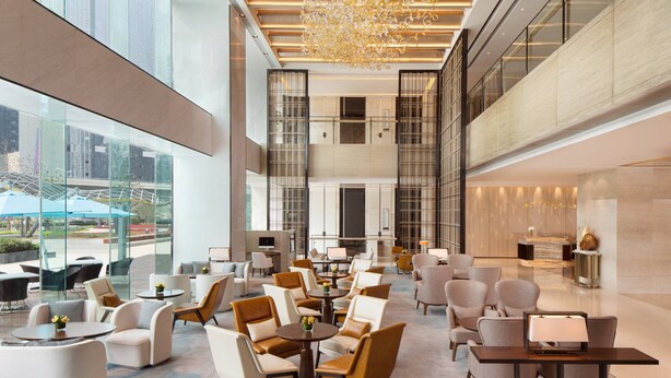 A spacious lobby with modern seating, a chandelier, and large windows offering views of the outside. - Courtyard by Marriott Zhengzhou East (Zhengzhou)