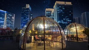Two transparent dome structures with tables and chairs, set against a city skyline at night. - Courtyard by Marriott Zhengzhou East (Zhengzhou)