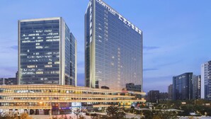 A modern hotel with a prominent 'Courtyard' sign, featuring a glass facade and a multi-story structure. - Courtyard by Marriott Zhengzhou East (Zhengzhou)