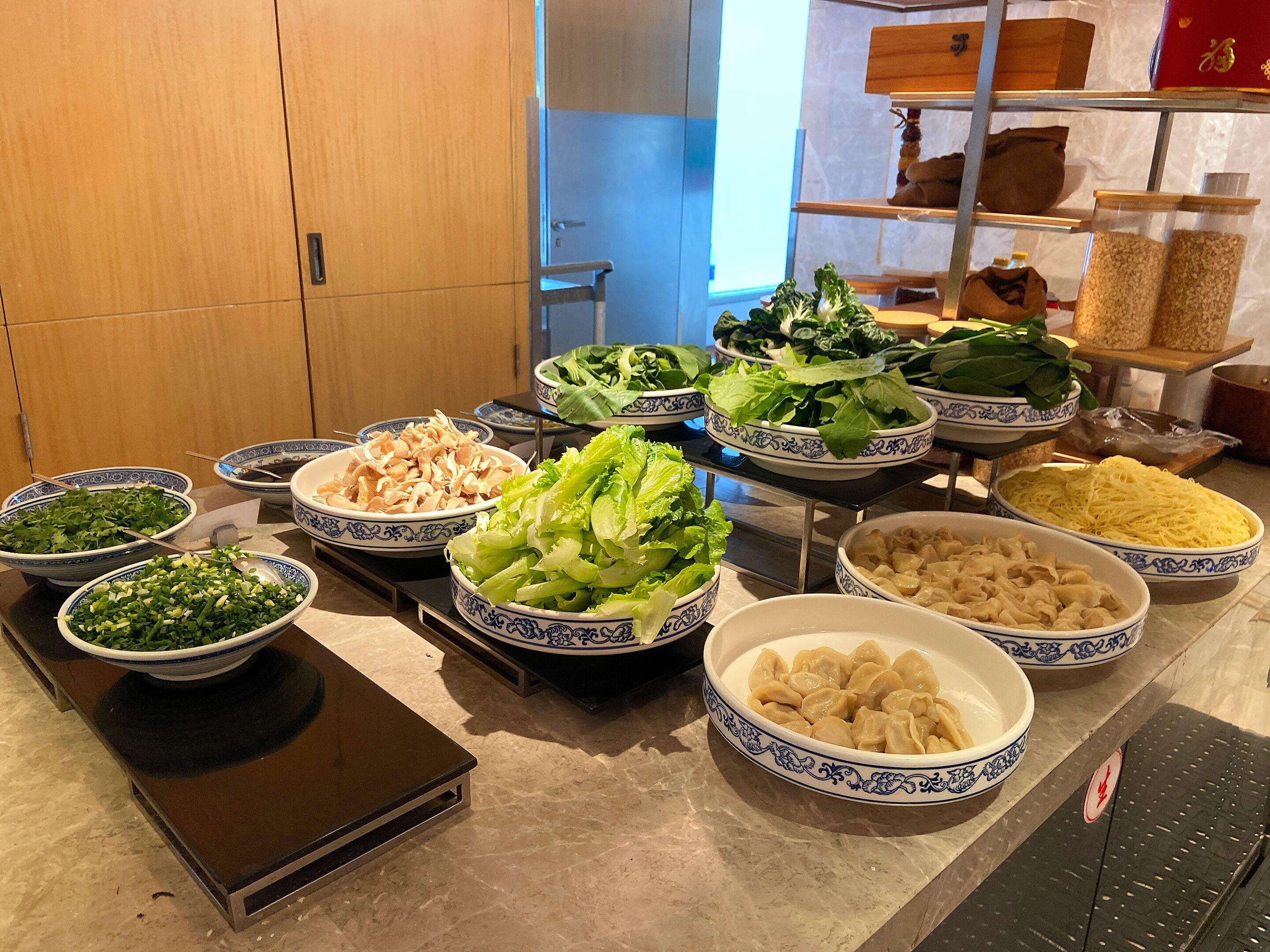 Una mesa de buffet con diversos platos, incluyendo verduras, fideos y albóndigas.