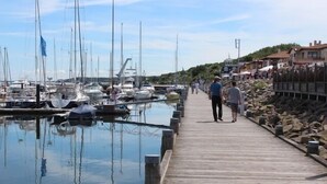 Une jetée en bois qui mène à une marina où sont amarrés des bateaux.