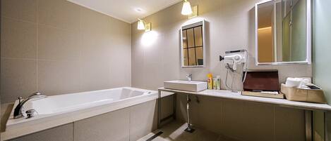 Un baño moderno con una bañera grande, un lavabo y un espejo. Hay luces en el techo y un secador de pelo en la encimera.