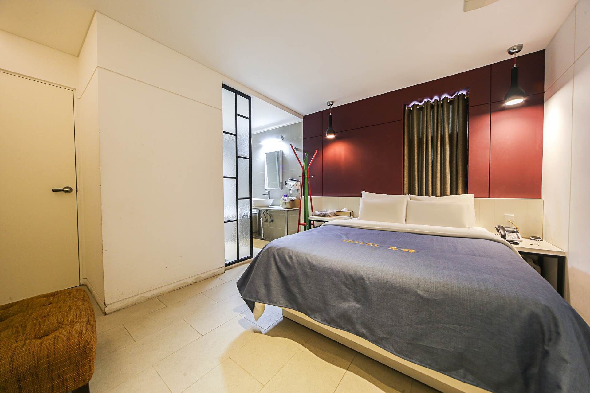 A hotel room with a bed, a desk, a chair, a mirror, and a wardrobe.