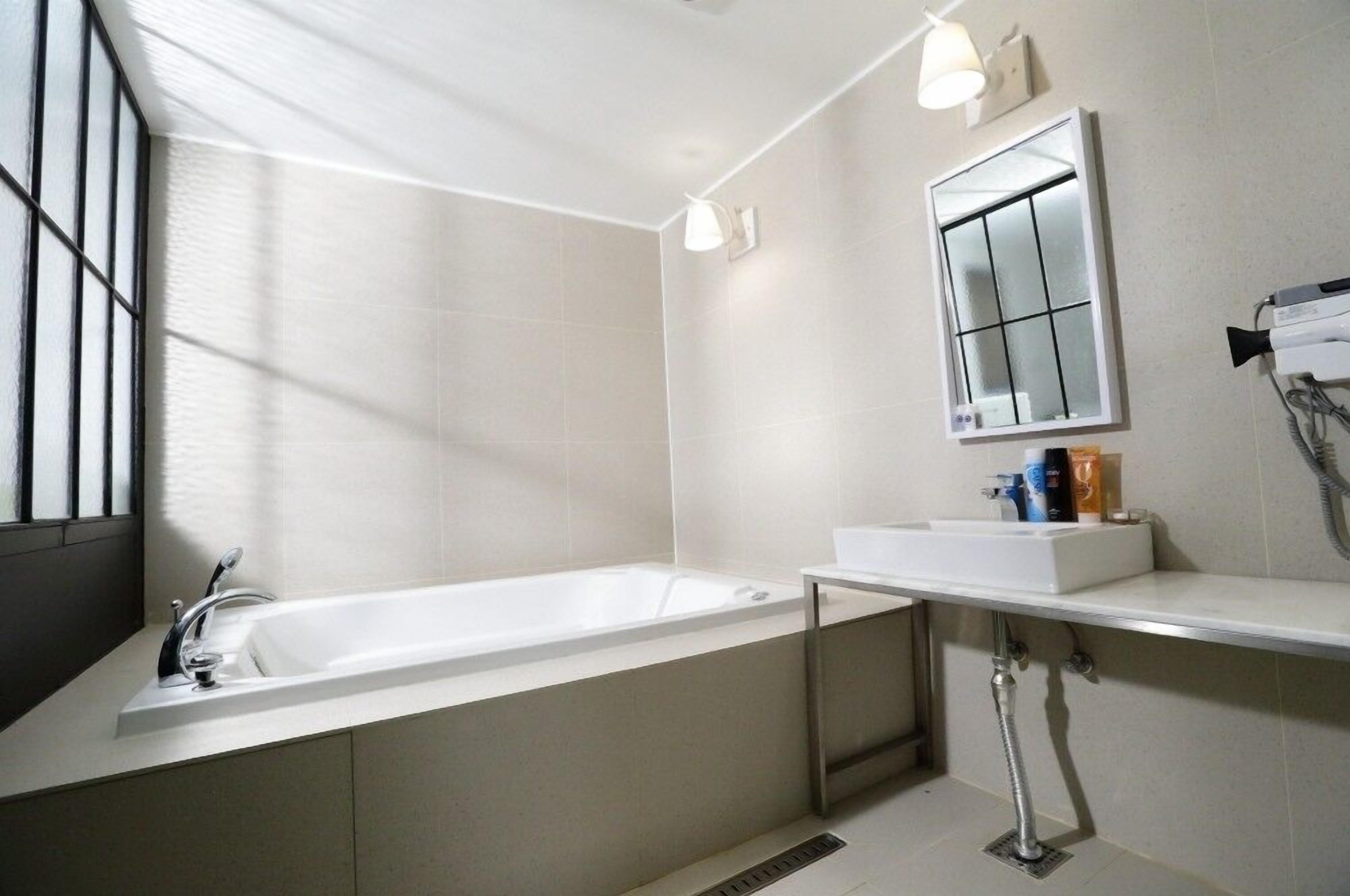 A modern bathroom with a bathtub, a vanity with a mirror, and a window providing natural light.