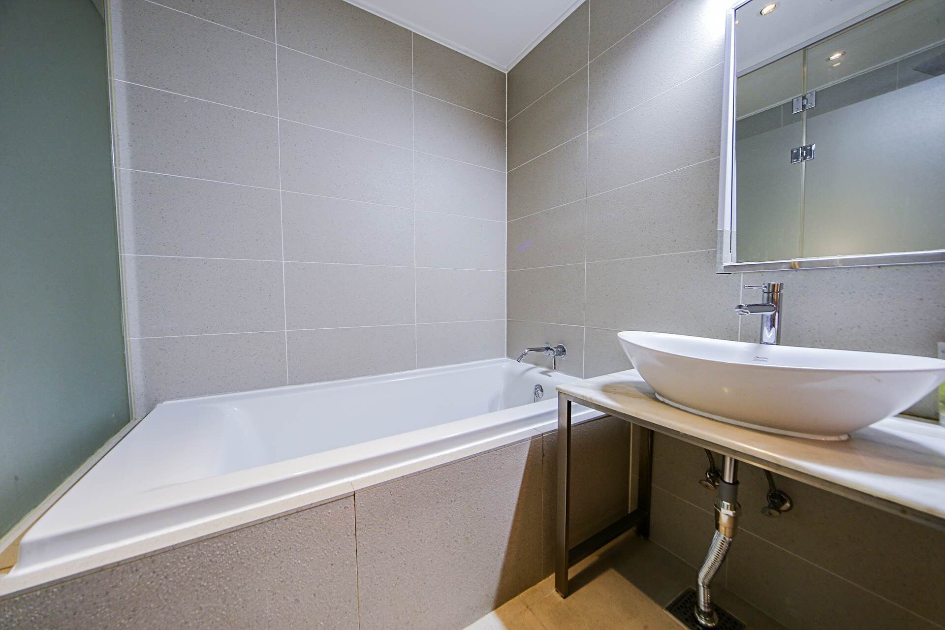 Une salle de bain moderne avec une baignoire sur pieds, un grand miroir et un lavabo posé sur un meuble.