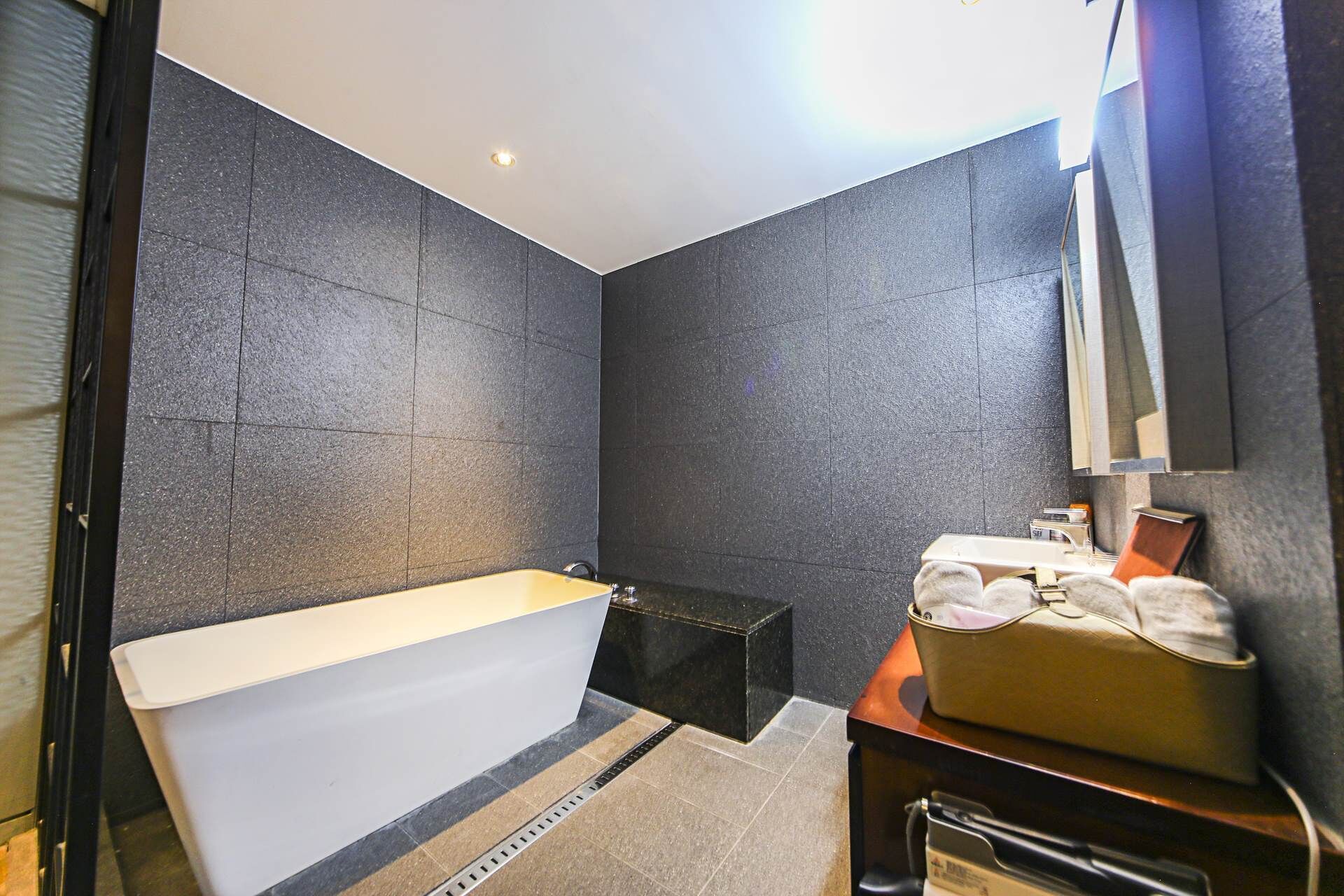 A modern bathroom with a bathtub, a vanity with a mirror, and a towel rack.