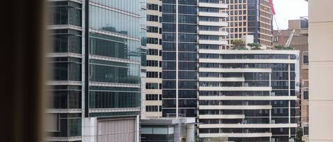 Un edificio moderno de rascacielos con varios pisos, amplias ventanas y una grúa de construcción al fondo.