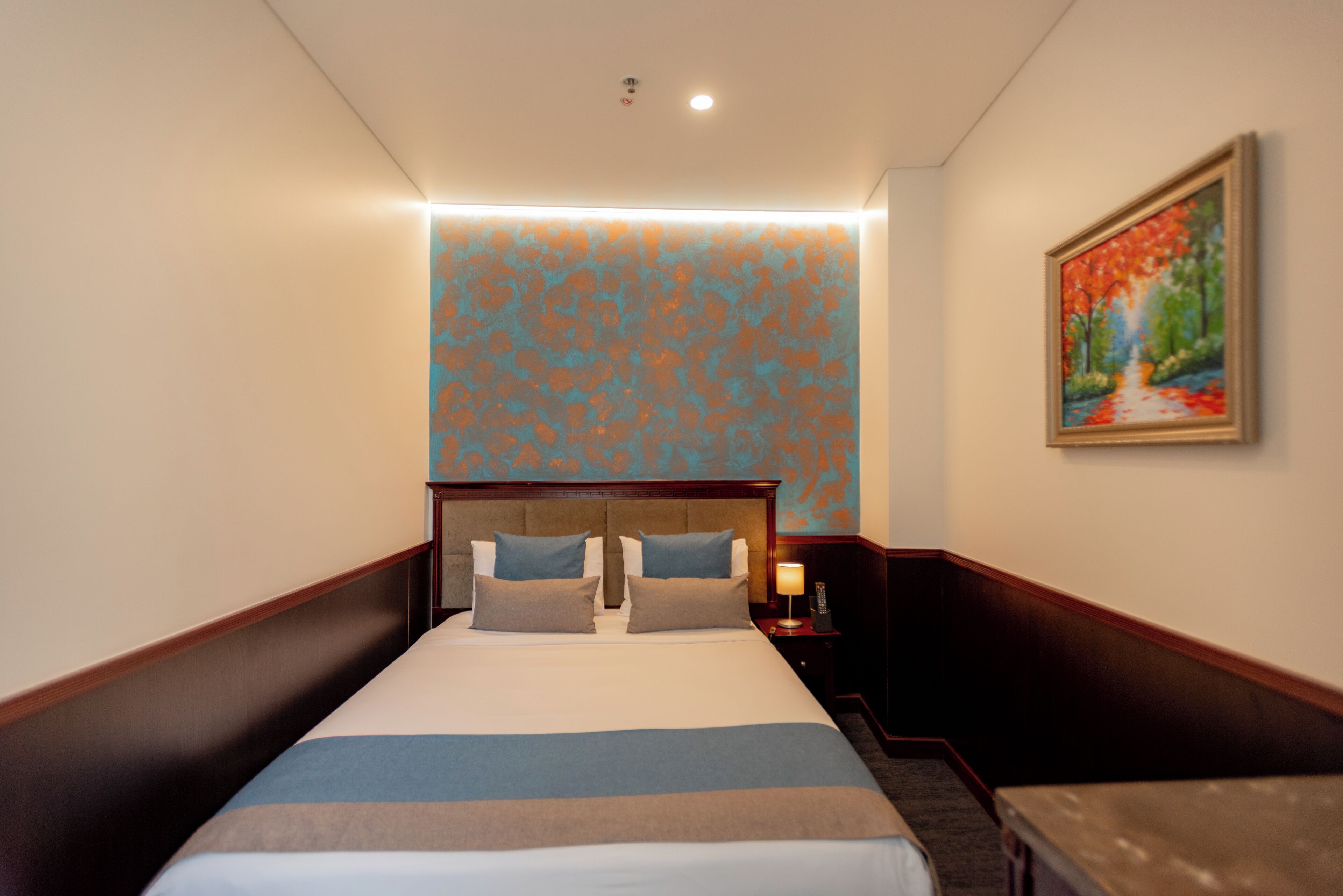 A hotel room with a large bed, a nightstand, a painting on the wall, and a staircase.