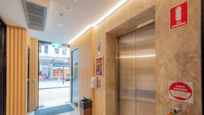 Un vestíbulo de hotel con una recepción, un extintor y un ascensor.