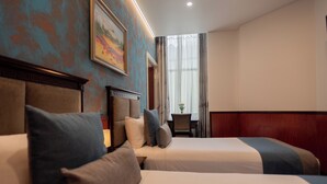 Una habitación de hotel con dos camas, un cuadro en la pared y un ventanal con cortinas.