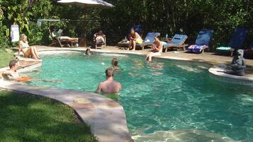 Relax by the pool surrounded by lush greenery and shaded lounge chairs.