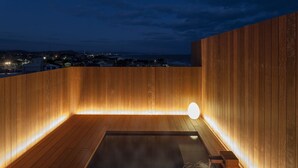 A wooden sauna with a heated floor and a small seating area, overlooking a cityscape at dusk. - Chikurakan (Minamiboso)
