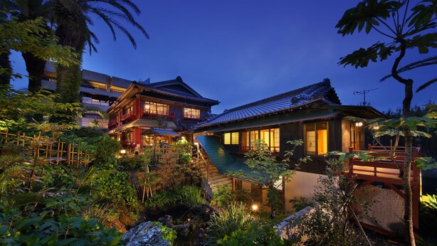 A traditional Japanese house with a wooden exterior, a stone pathway, and a small pond. - Chikurakan (Minamiboso)