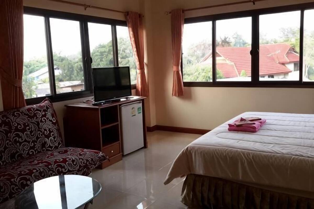 A hotel room with a bed, a sofa, a small TV, and a desk.