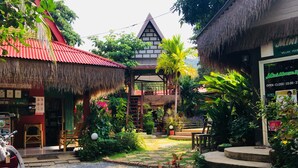 A courtyard with a thatched-roof structure, a small seating area, and a shop with a massage service sign.