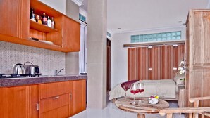 A modern kitchen with wooden cabinets, a countertop, and a dining area with a round table and chairs. - Kuta EcoStay (Kuta)