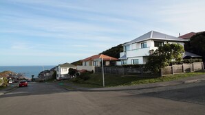 A residential street with houses, a clear sky, and a view of the sea. - Pacific View Bed and Breakfast (Wellington)