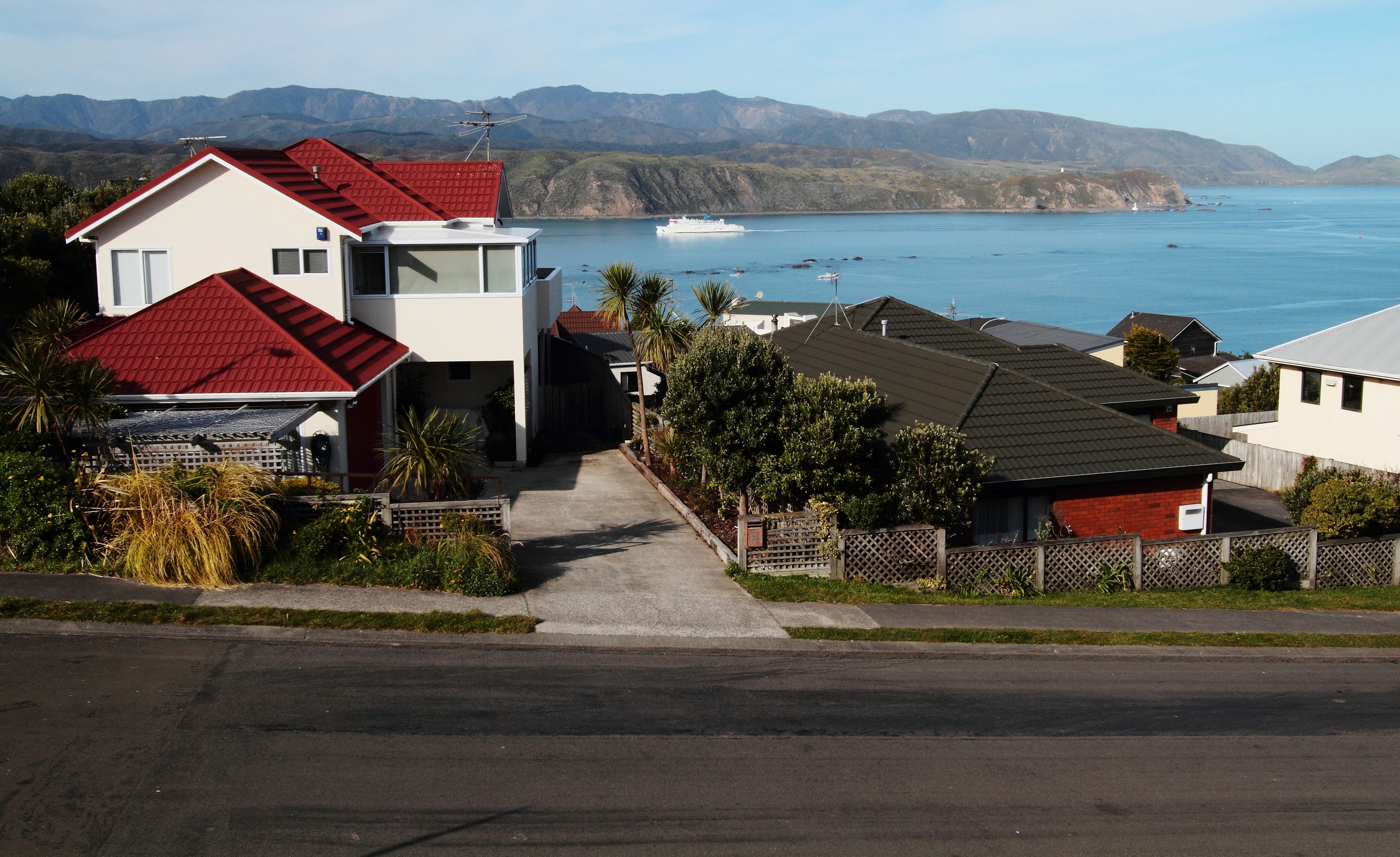 Uma área residencial com casas, vista clara do oceano e montanhas ao fundo.