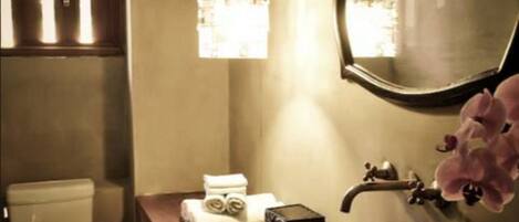 A bathroom with a toilet, a sink with a mirror, a towel rack, and a small plant.